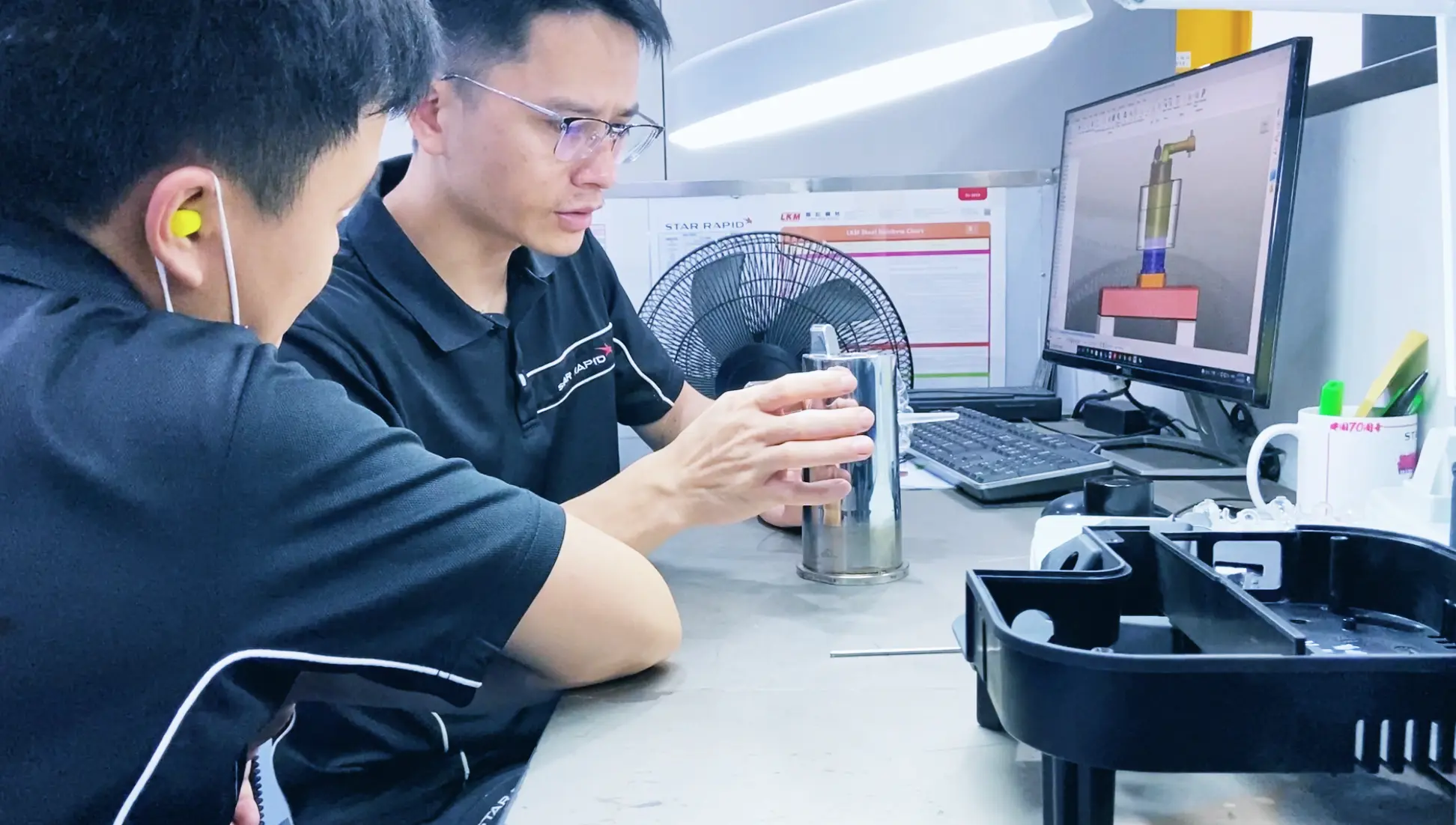 wo men reviewing machine parts at desk and on a monitor