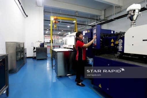 Worker operating plastic injection molding machine at Star Rapid